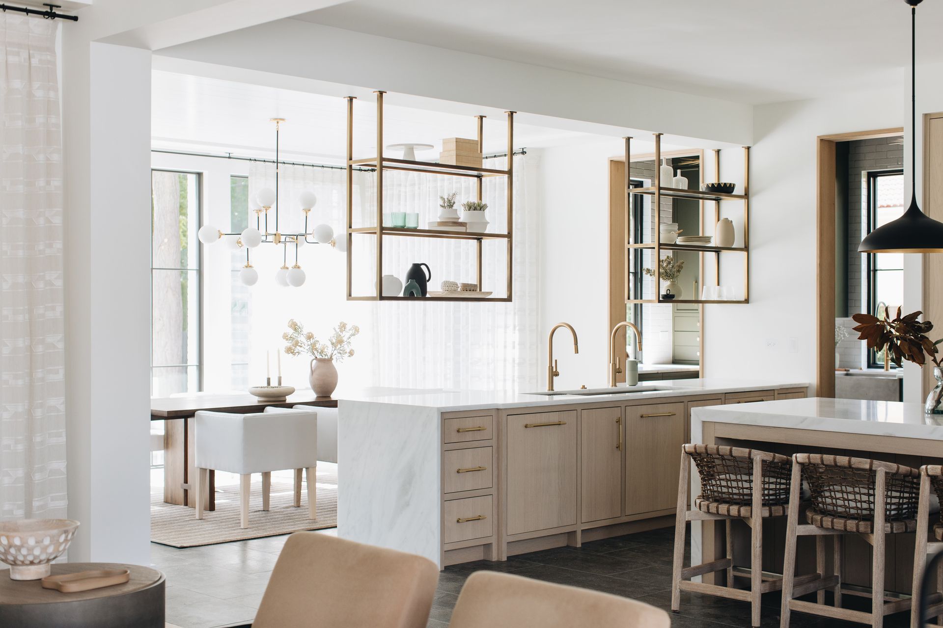 Bright modern kitchen with white cabinets, wood shelves, and a dining table in an open-plan home