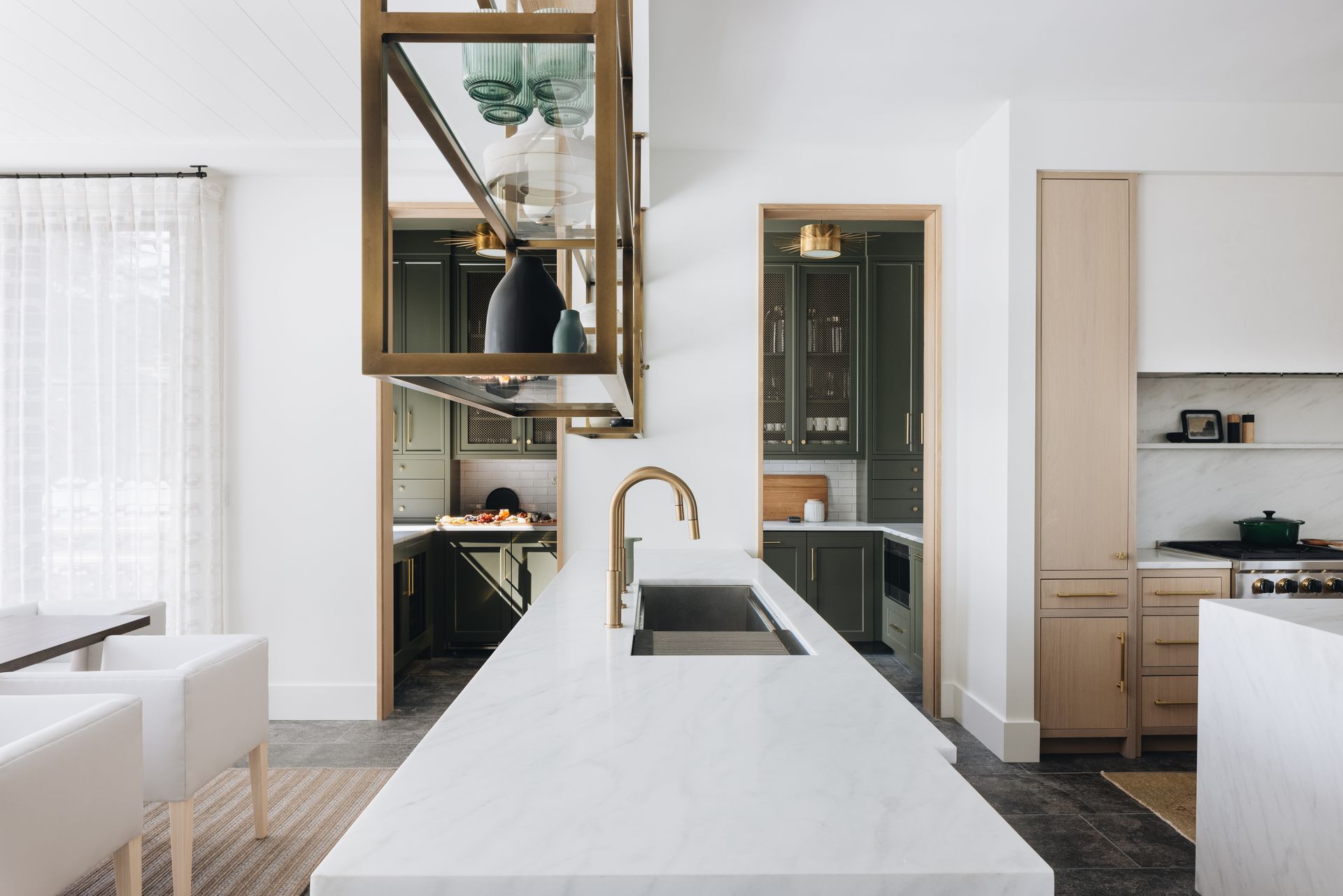 Modern kitchen with white island, brass faucet, and large hanging mirror in a bright open space