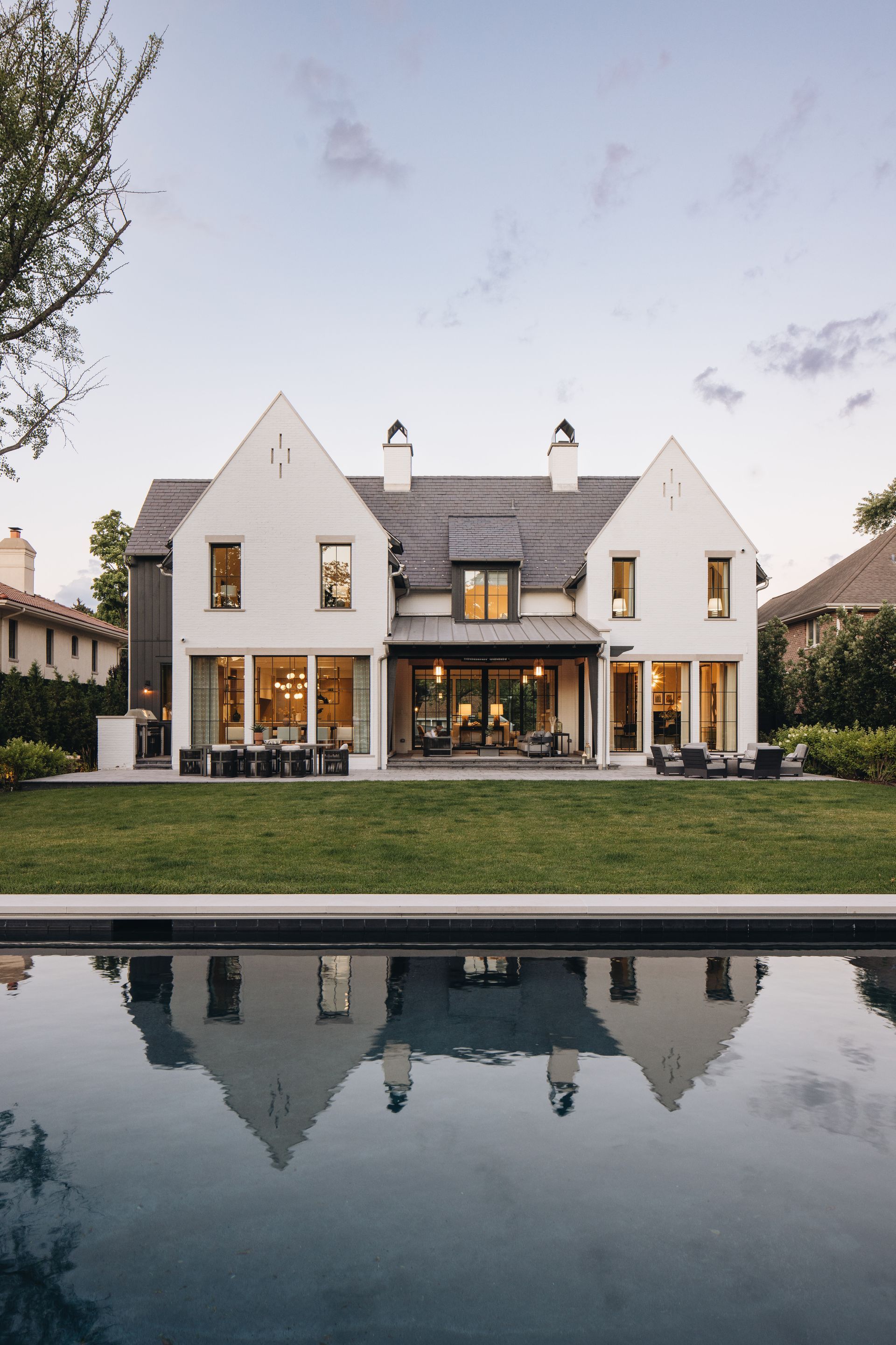 White modern villa with a reflecting pool in front at dusk