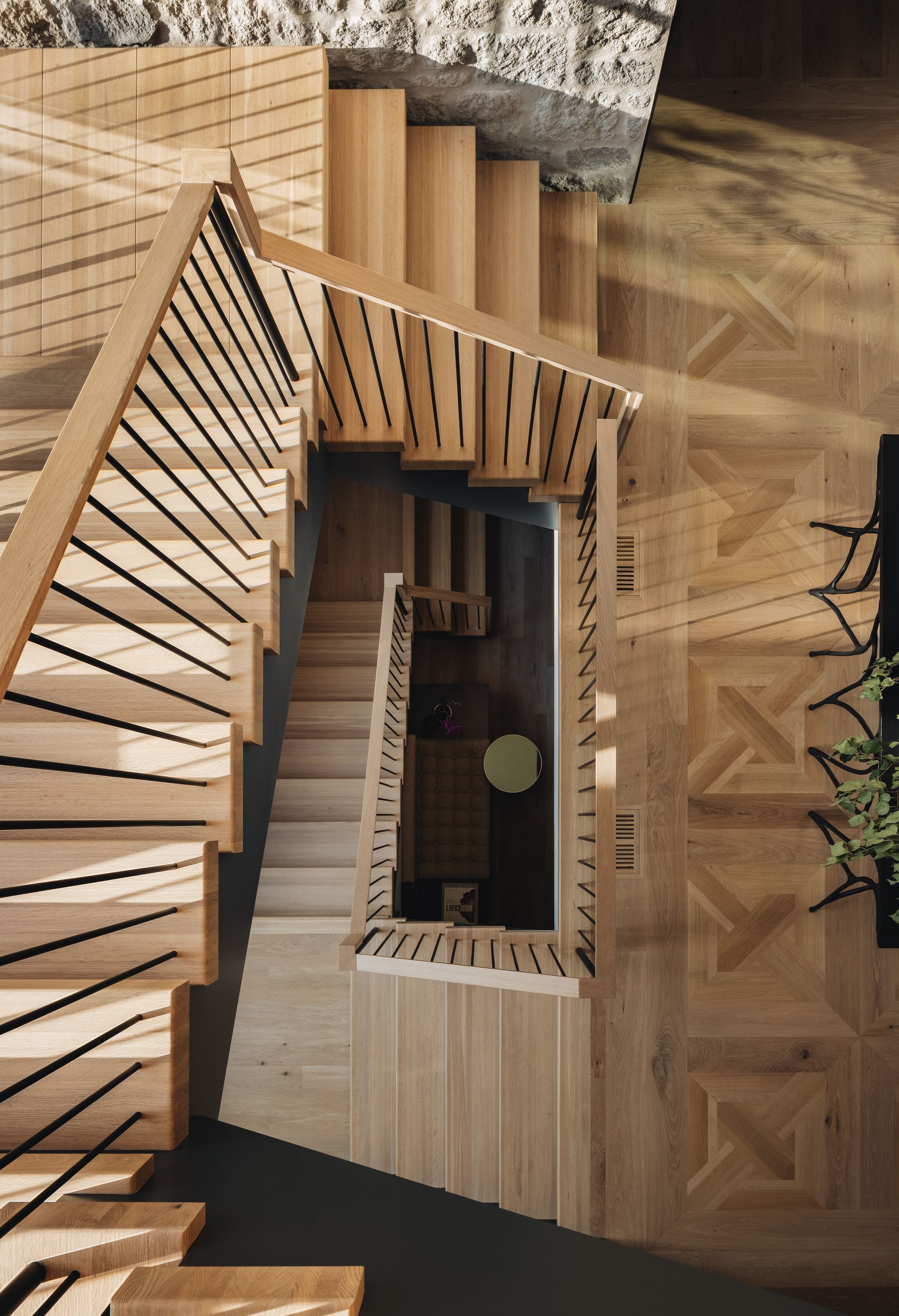 Spiral wooden staircase around a central open atrium with a patterned wood floor below