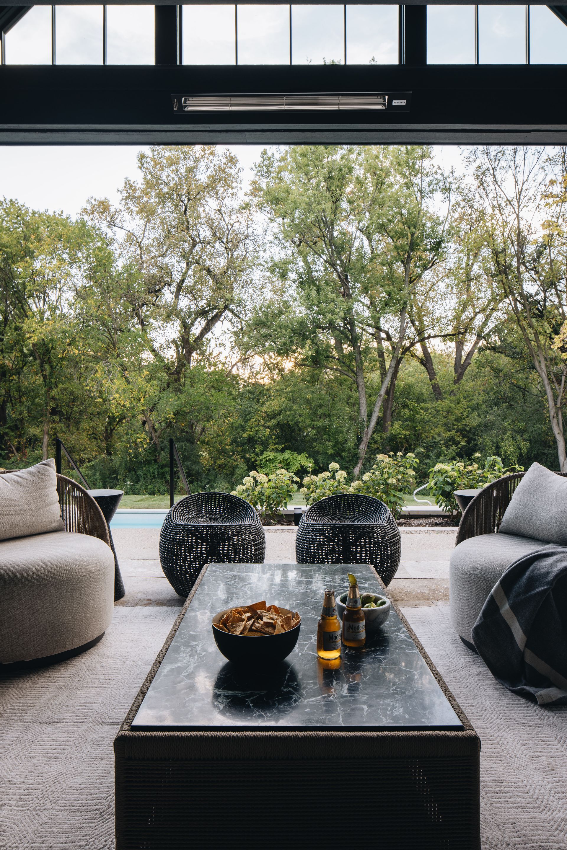 Modern patio lounge with low table, sofas, and garden view through open doors