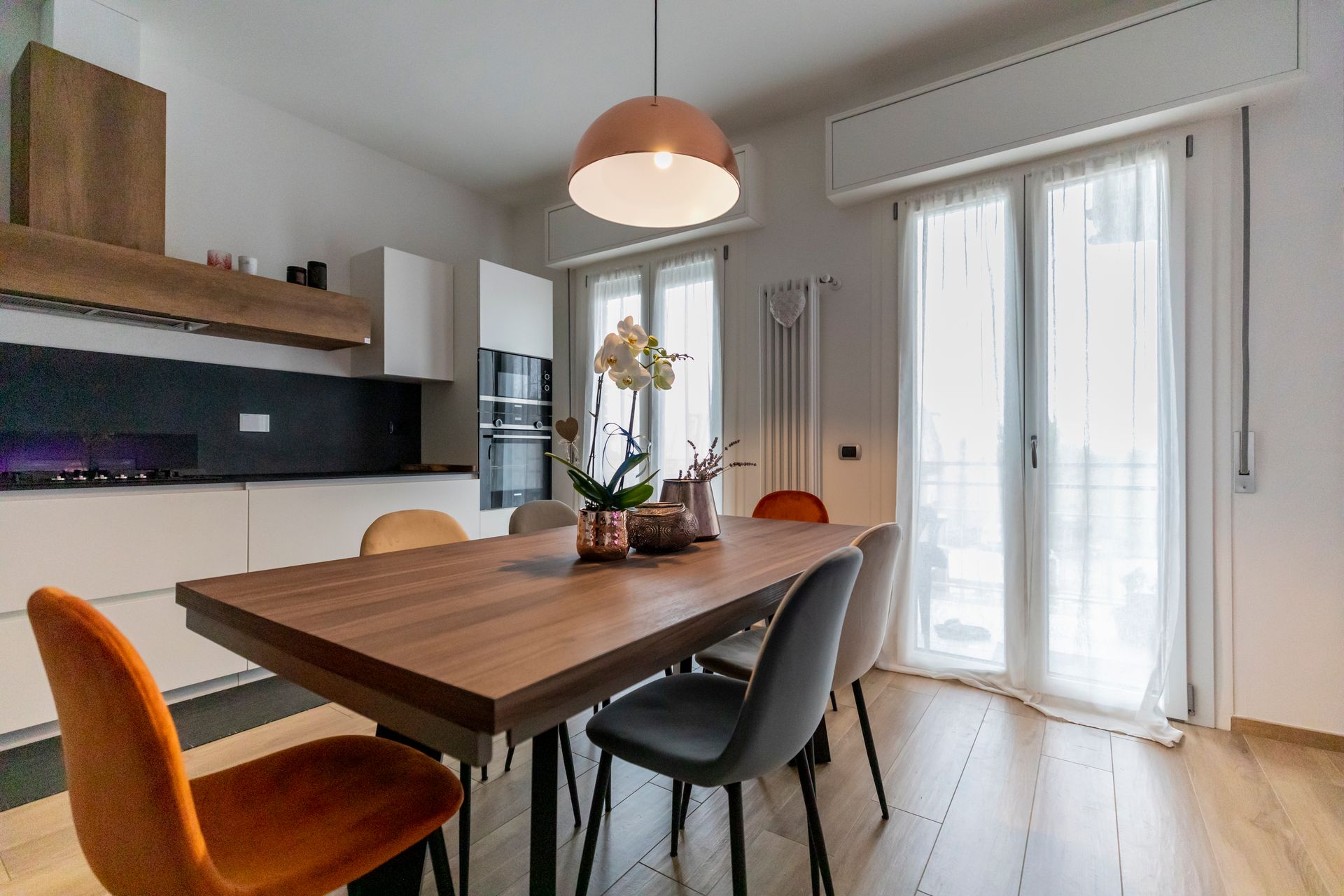 cucina con tavolo, sedie e porte-finestre