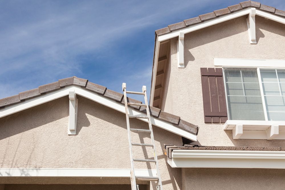Casa a due piani in costruzione con impalcature e pareti esterne grigie non rifinite.