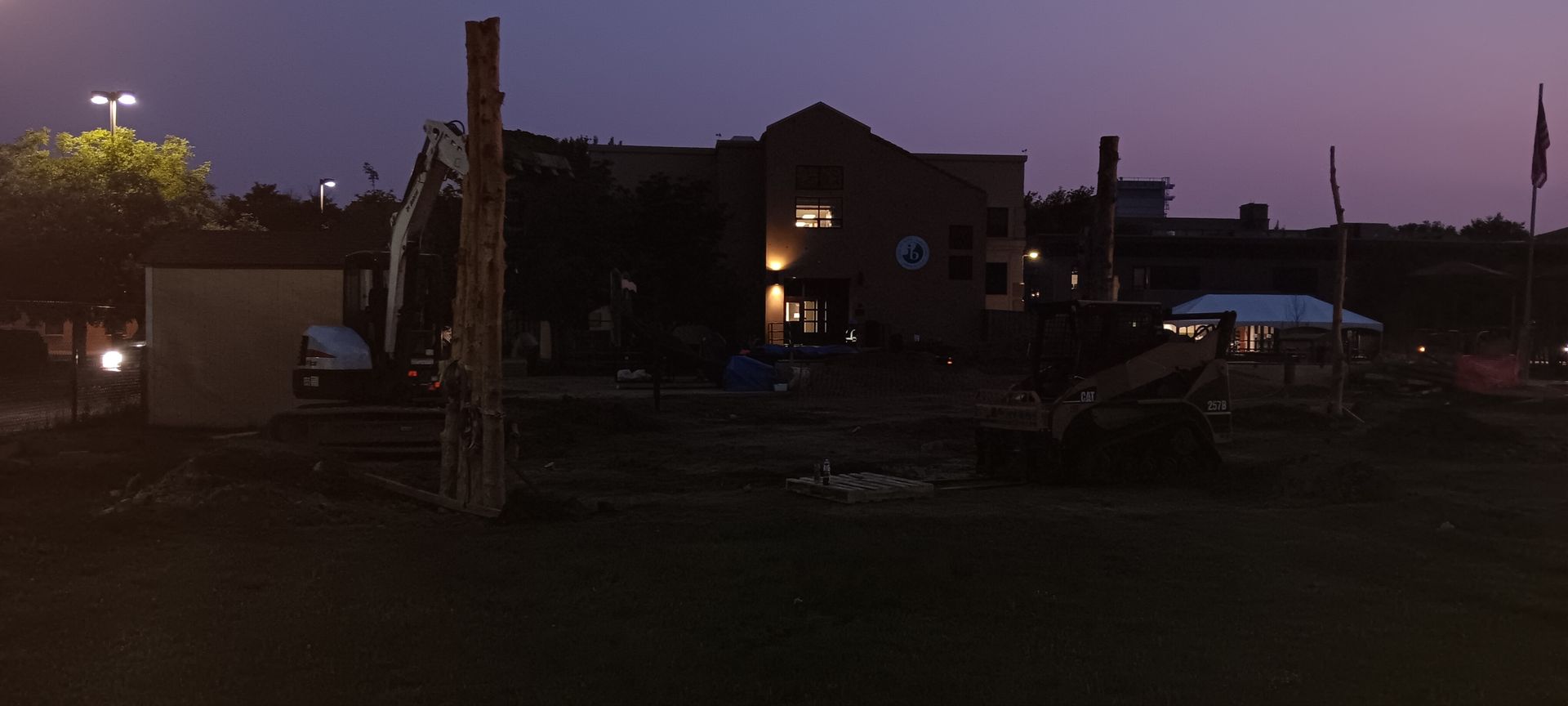 A construction site at night with a building in the background.