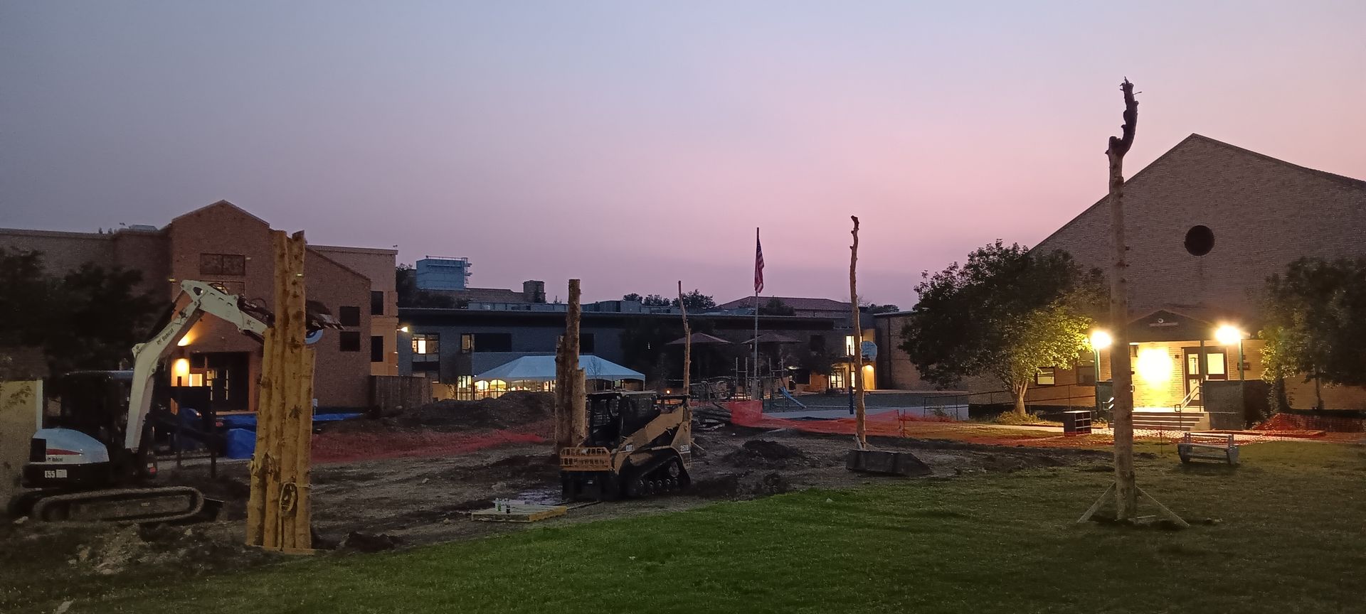 A construction site at night with a sunset in the background.