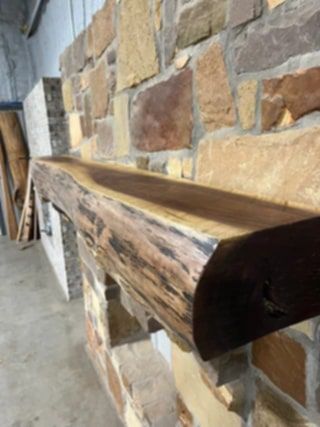 A wooden mantle is hanging on a brick wall.