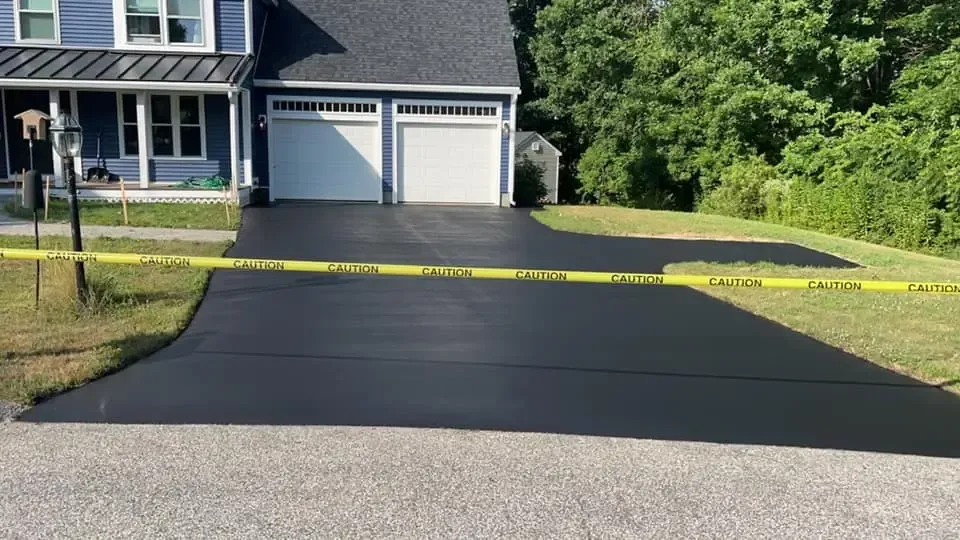Fresh black asphalt driveway in front of a house, blocked by yellow caution tape