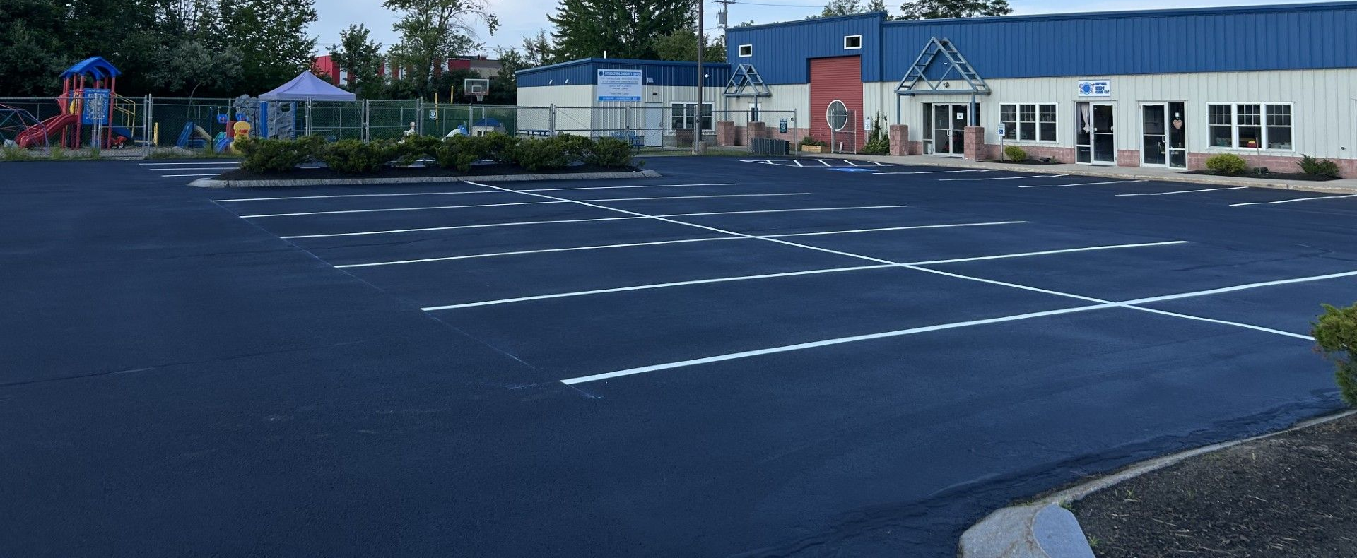 Empty parking lot with painted white lines outside low buildings on a sunny day