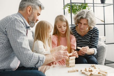 Family playing a tabletop stacking game in a bright living room