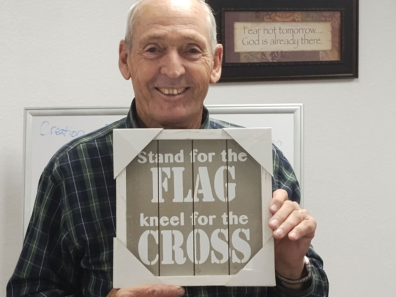 A smiling person holds a sign that reads: