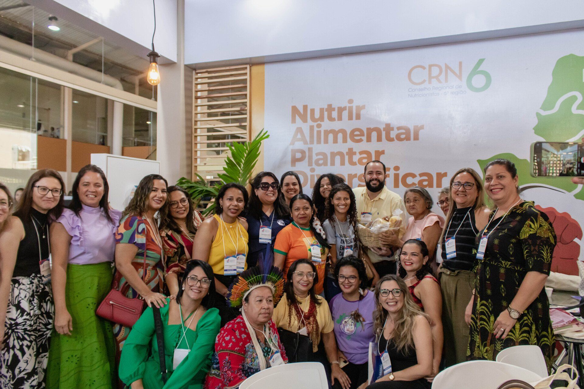 Um grupo de mulheres está posando para uma foto em frente a uma parede que diz nutrir alimentar plantar.