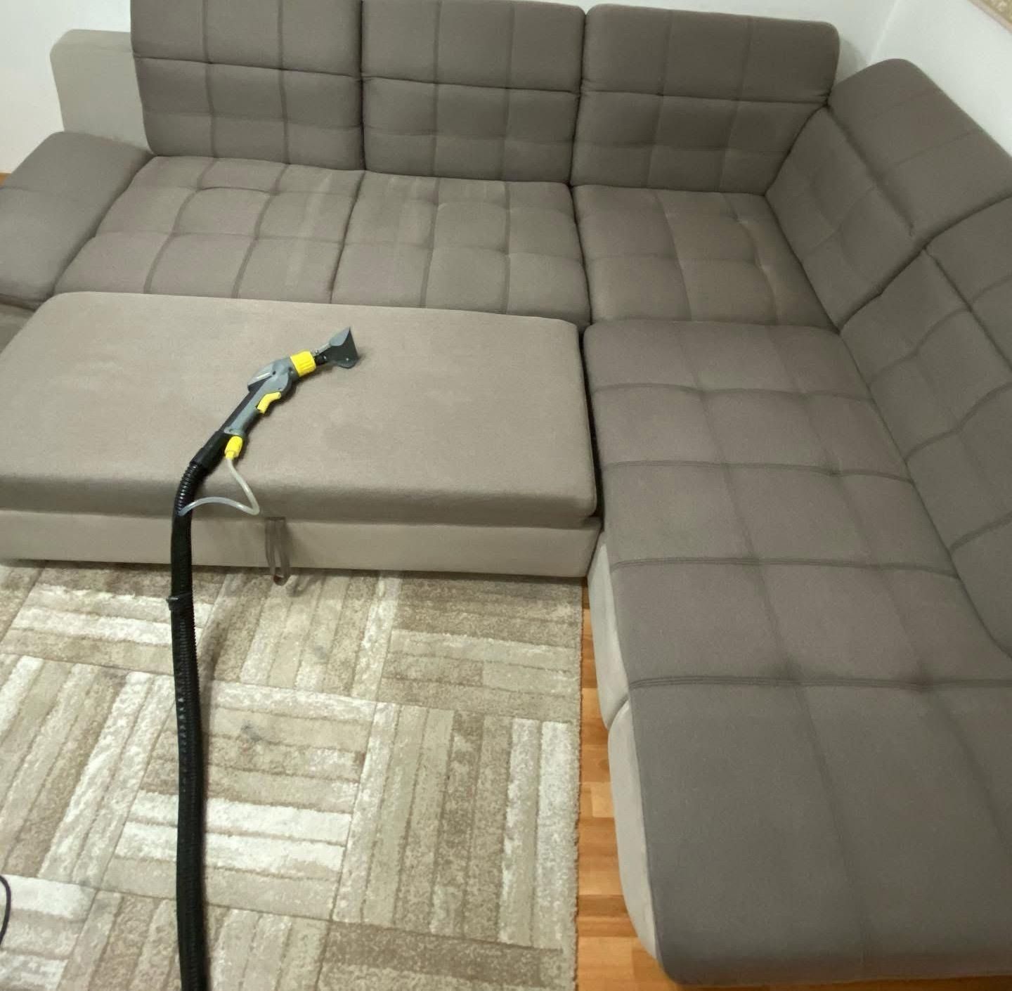 Divano componibile grigio con chaise longue e pouf in soggiorno, con seduta in canna nera.