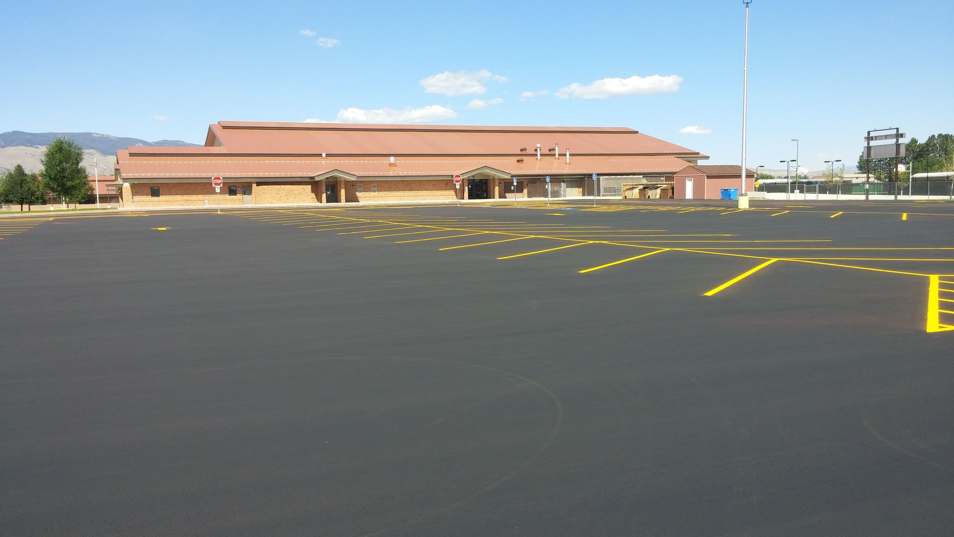 Empty parking lot in front of a low brick building on a clear day