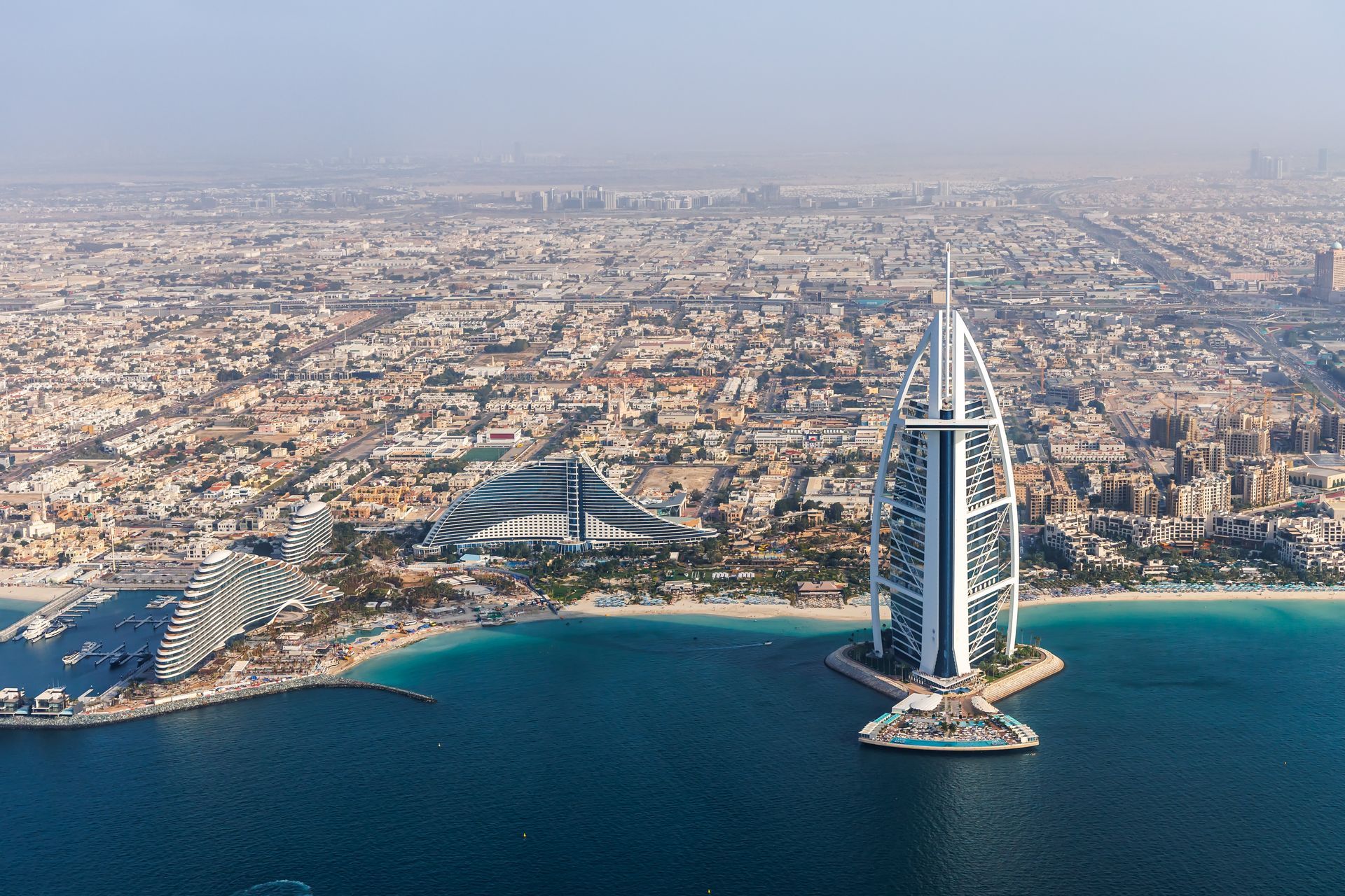 Dubai skyline with the Burj Al Arab hotel, buildings, and ocean.