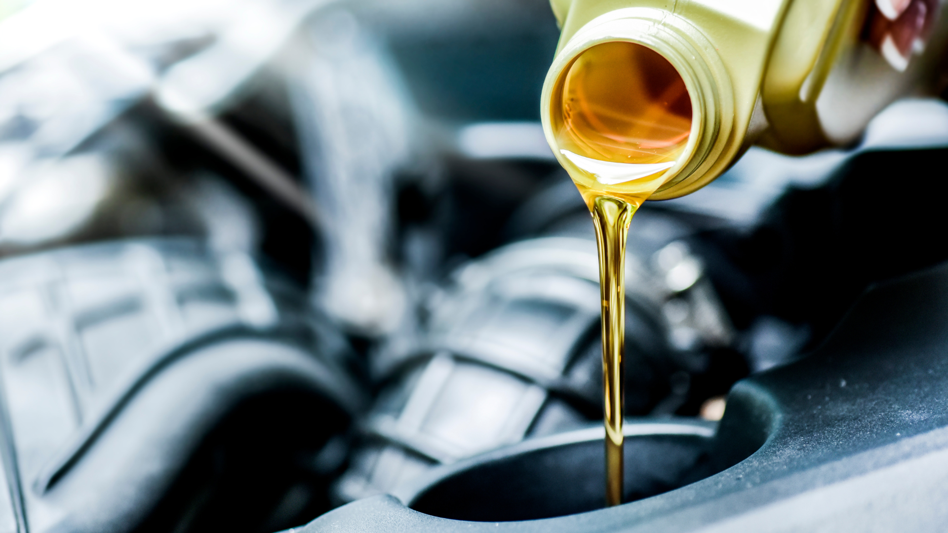 A person is pouring oil into a car engine.