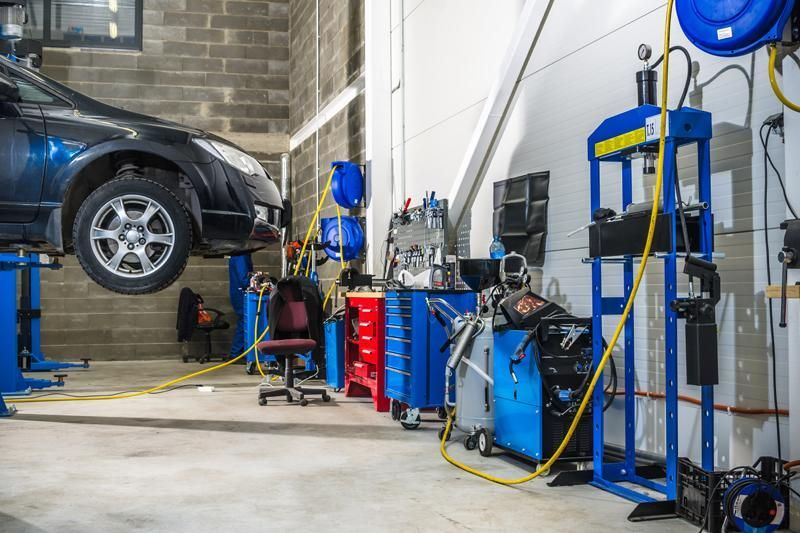 Voiture sur un pont élévateur dans un garage avec des outils et de l'équipement.