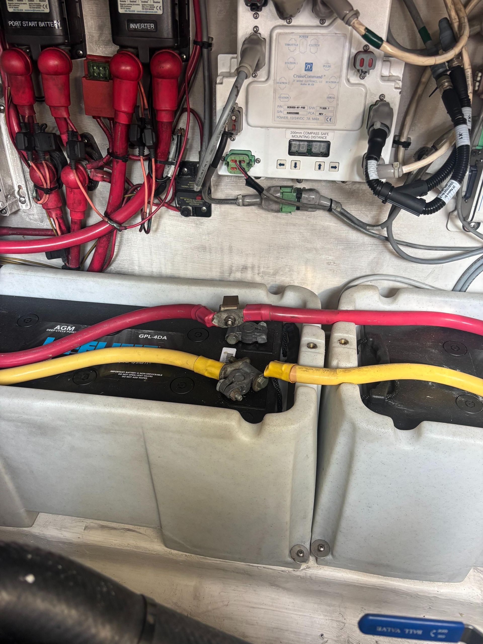 Two white battery boxes with red and yellow cables, located near electrical components.