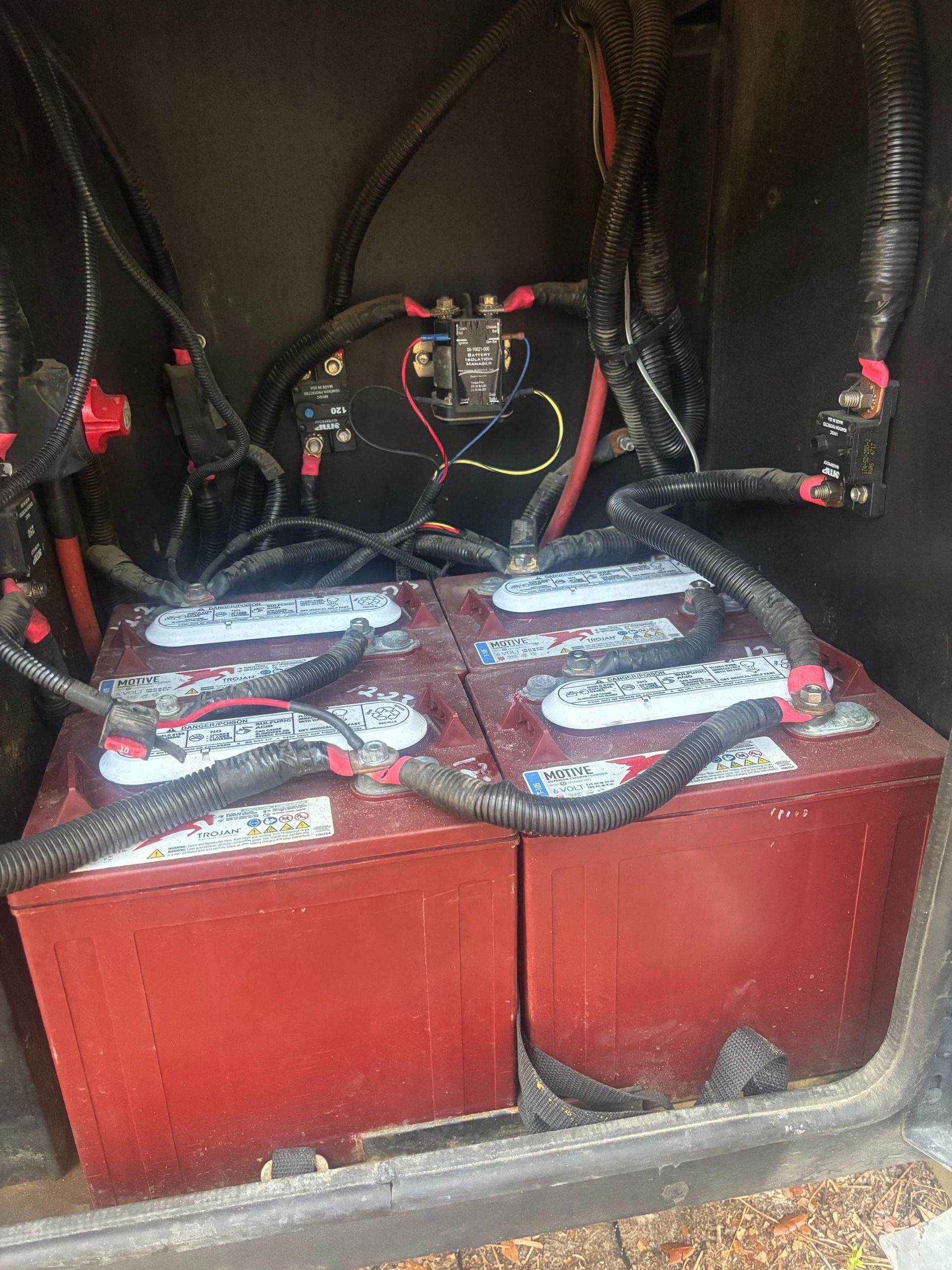 Four red batteries wired together in a compartment, with wiring and electrical components visible.