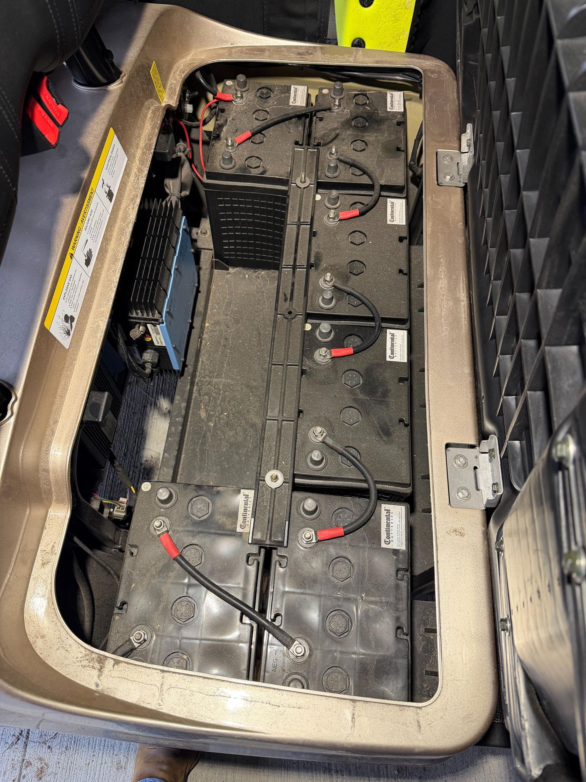 Inside view of golf cart battery compartment with six black batteries and wiring.