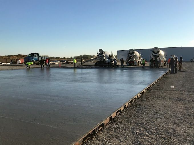 A group of construction workers are working on a concrete floor