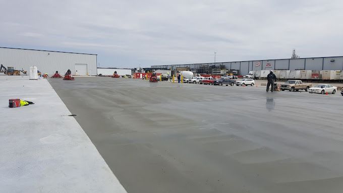 A large concrete parking lot with a lot of cars parked in it