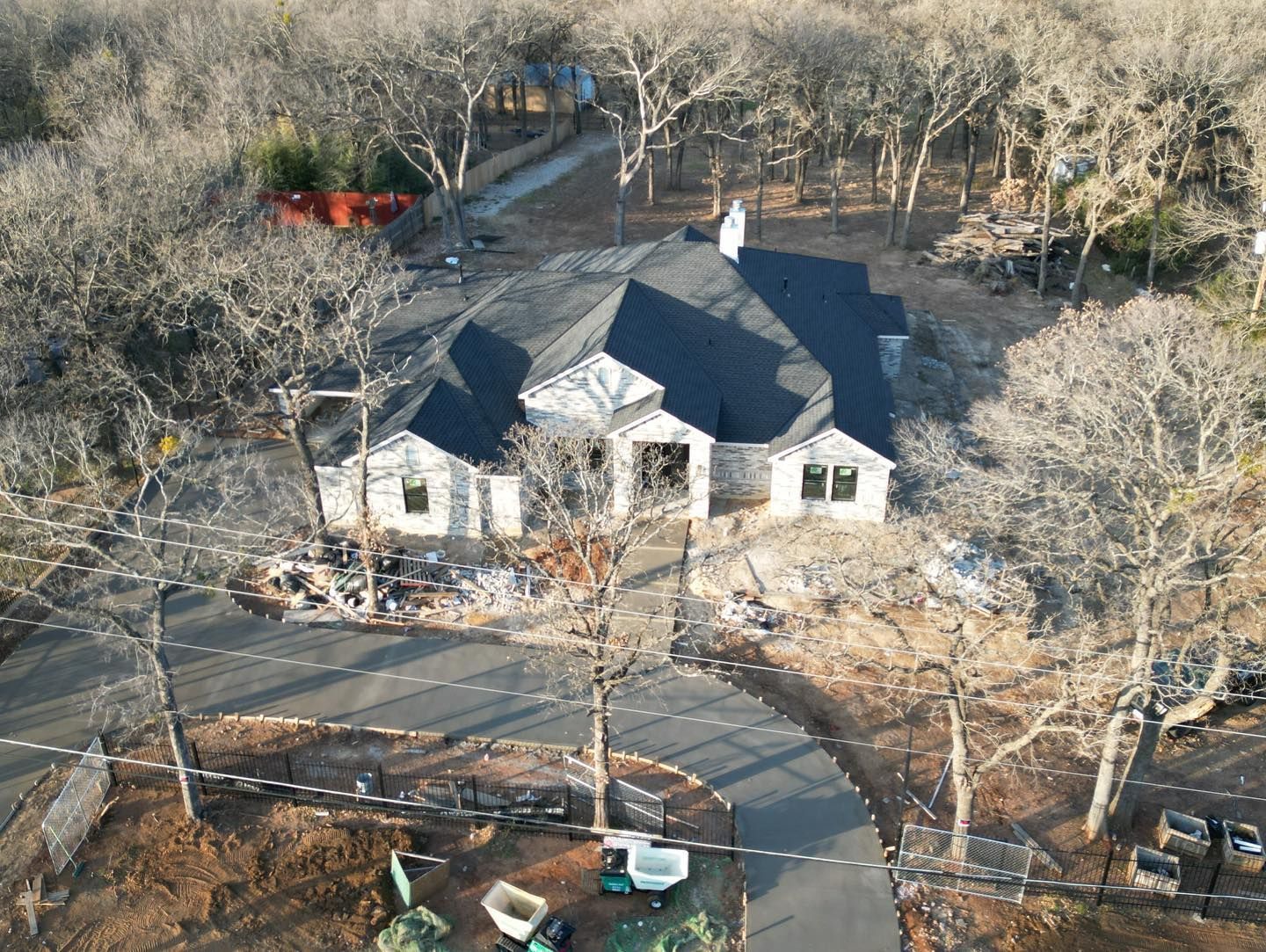Aerial view of a house surrounded by trees, driveway in front.