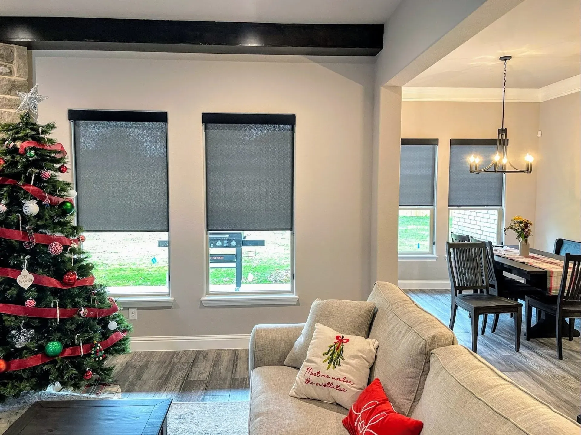 a living room with a couch, roller shades on the windows and a christmas tree Love is Blinds.