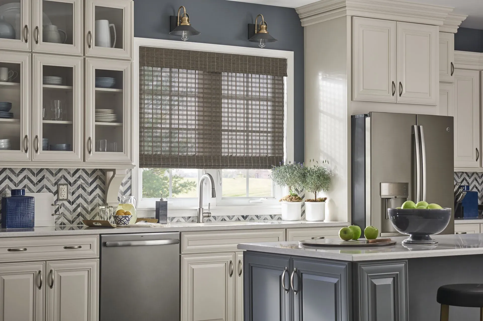 A kitchen with white cabinets , stainless steel appliances , and woven wood shades on the window.