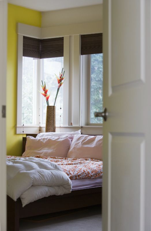 a bedroom with a bed , window , and yellow walls honeycomb shades bedroom Love is Blinds Kentucky (859) 549-3177.
