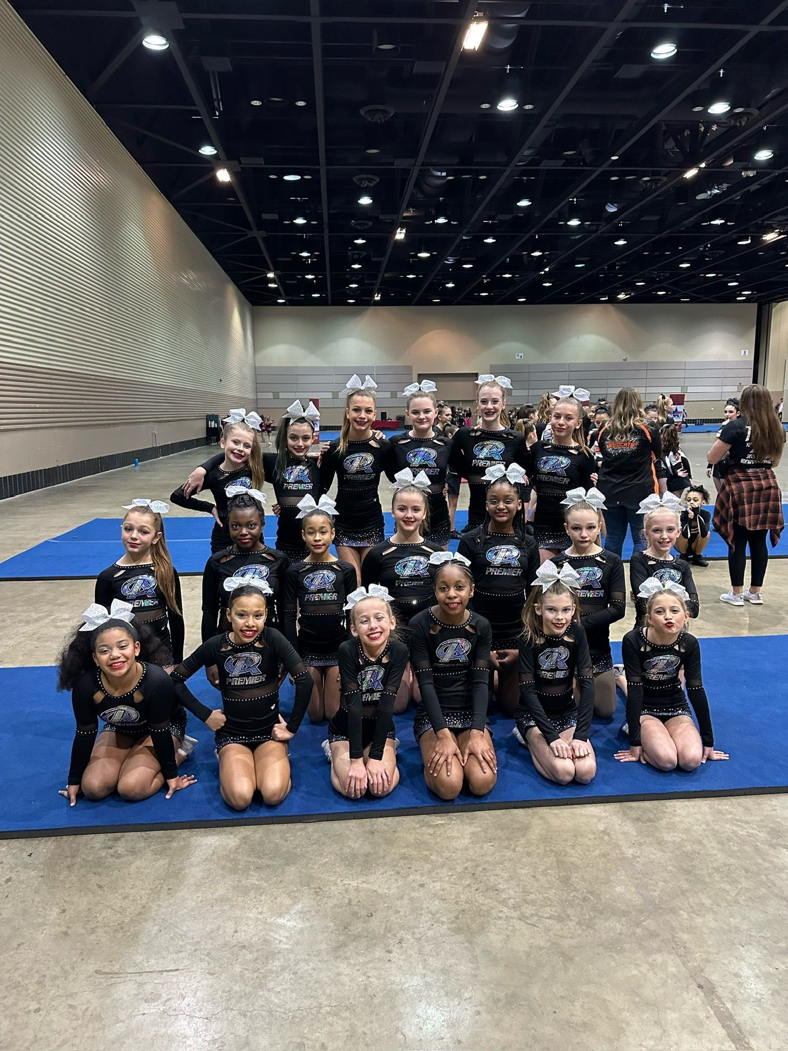 A group of cheerleaders are sitting in a circle in a dark room.
