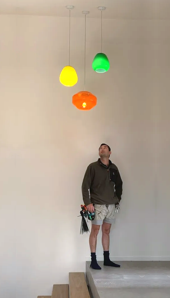 A Man Staring Up at a Set of Pendant Lights — Aliance Group in Bonville, NSW 