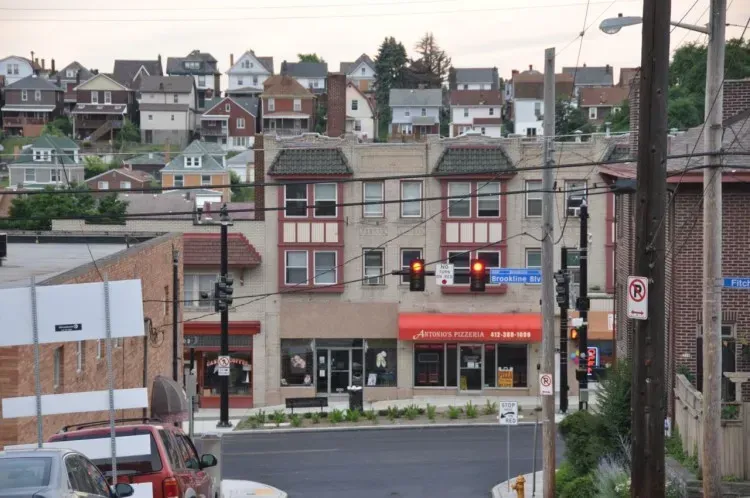 A red car is parked in front of a building with a red awning