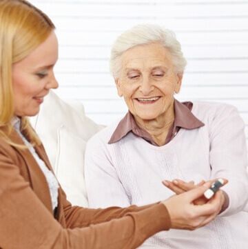 A woman is giving an elderly woman a pill.
