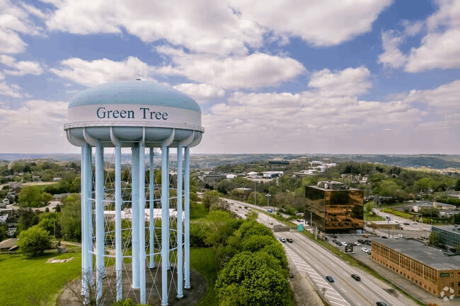 An aerial view of a water tower in green tree.