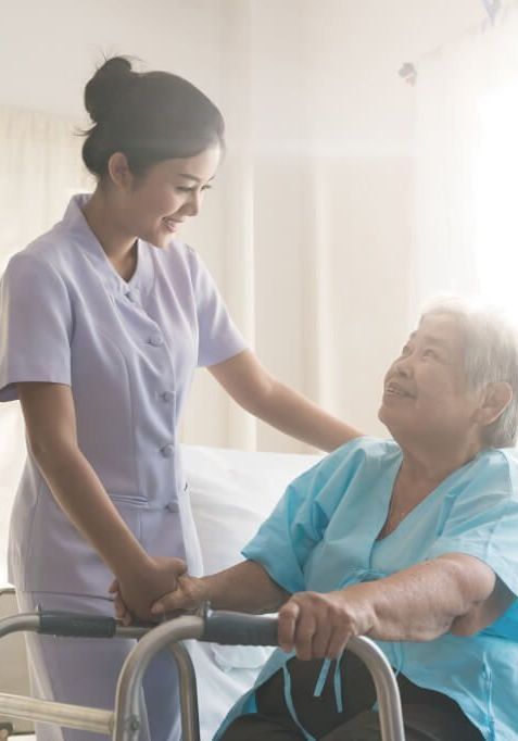 A nurse is helping an elderly woman in a hospital bed with a walker.