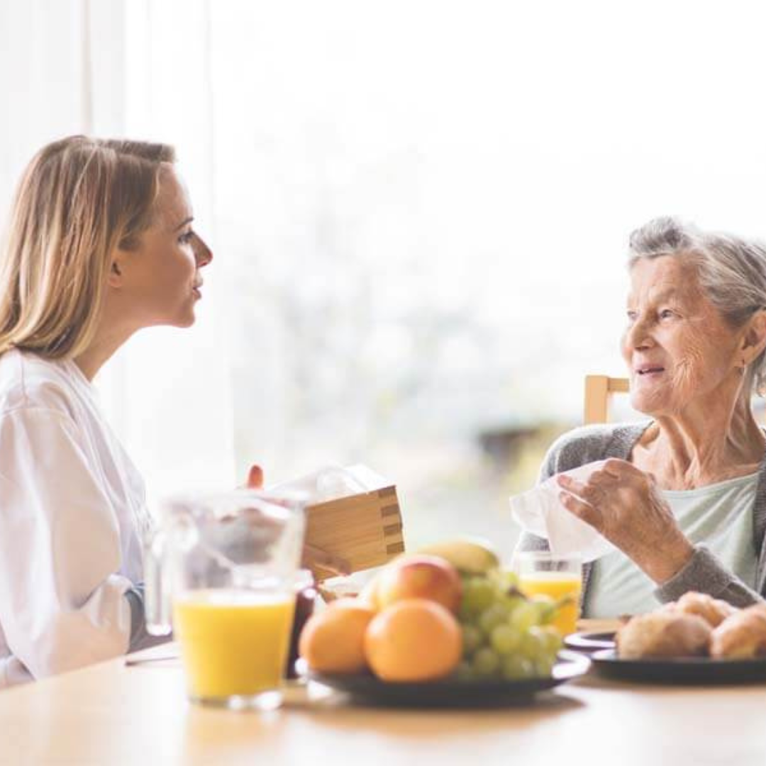 Two women are sitting at a table talking to each other.