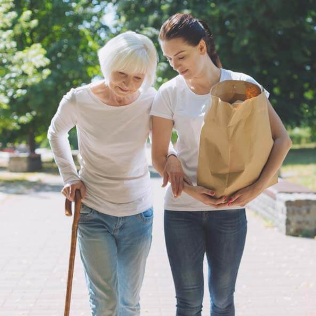 A woman is helping an older woman walk with a cane.