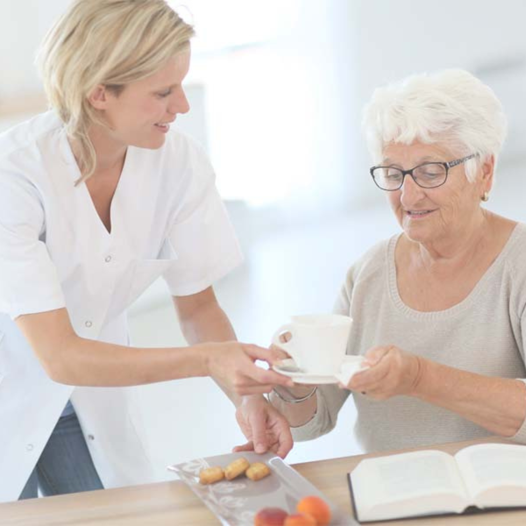 A woman is giving an older woman a cup of coffee