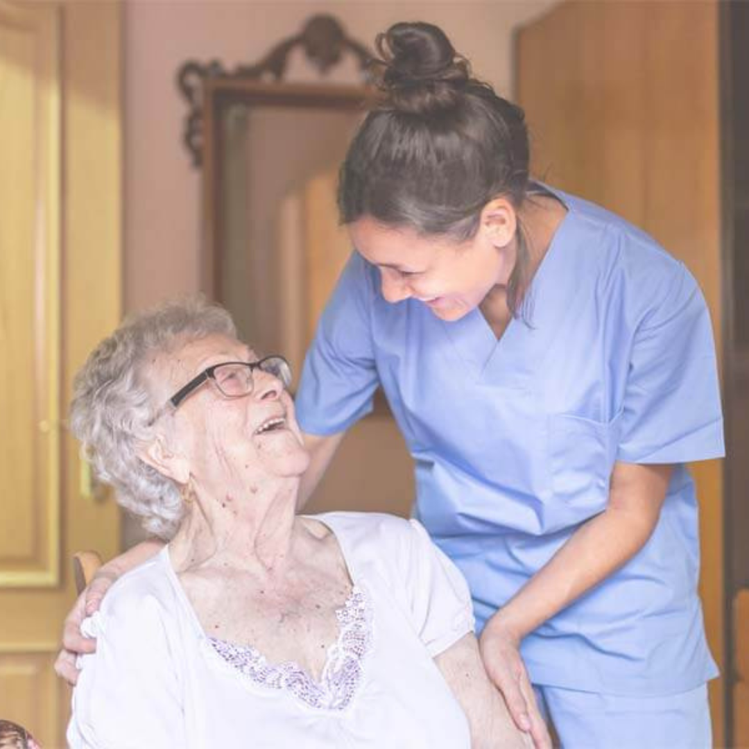 A nurse is talking to an elderly woman in a chair.