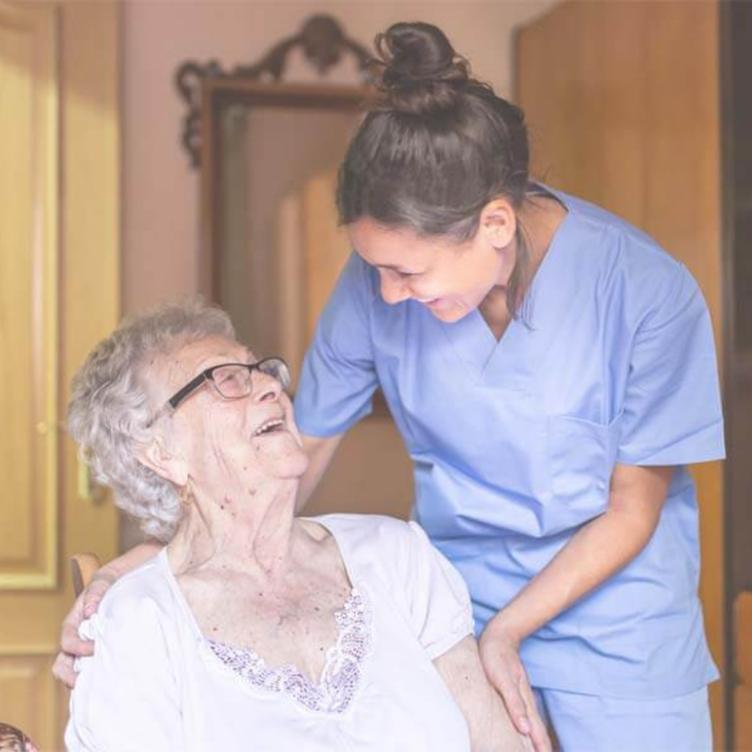 A nurse is talking to an elderly woman who is sitting in a chair.