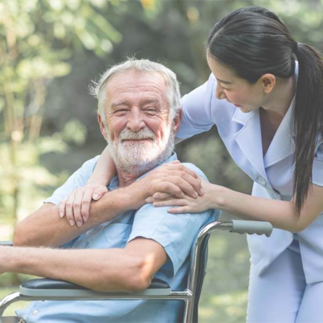 An elderly man in a wheelchair is being helped by a nurse.
