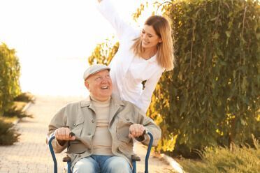A female aging coach is working with her elderly male patient outdoors on a sunny day.