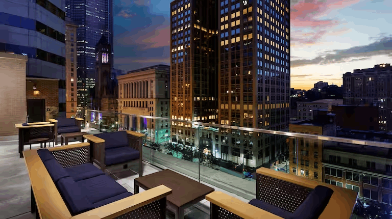 A balcony with chairs and tables overlooking a city at night.