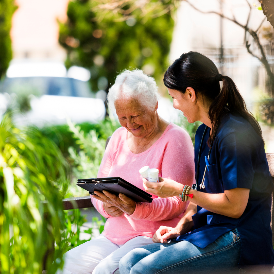Two women are sitting on a bench looking at a tablet.