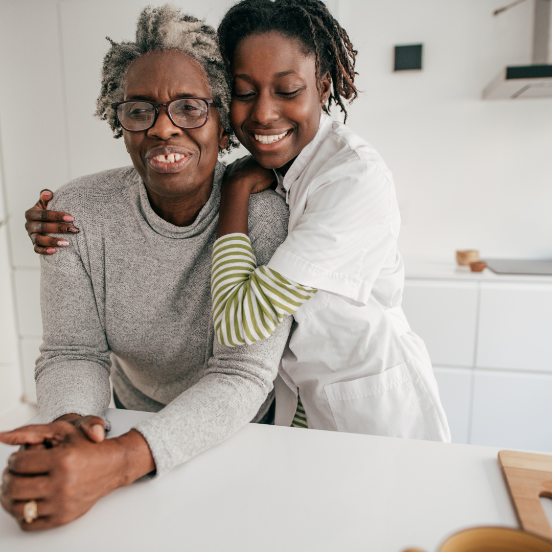 A woman is hugging an older woman in a kitchen.