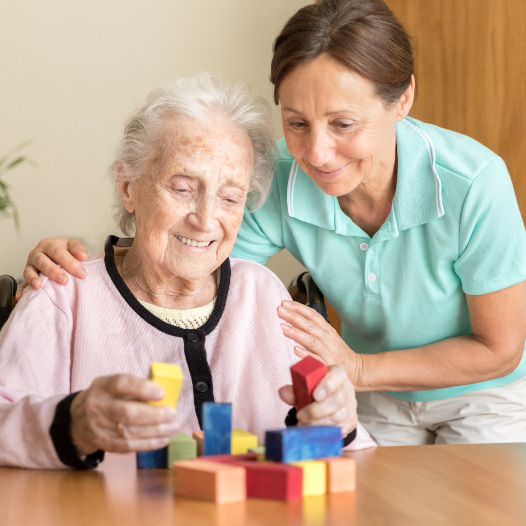 A woman is helping an elderly woman play with wooden blocks.