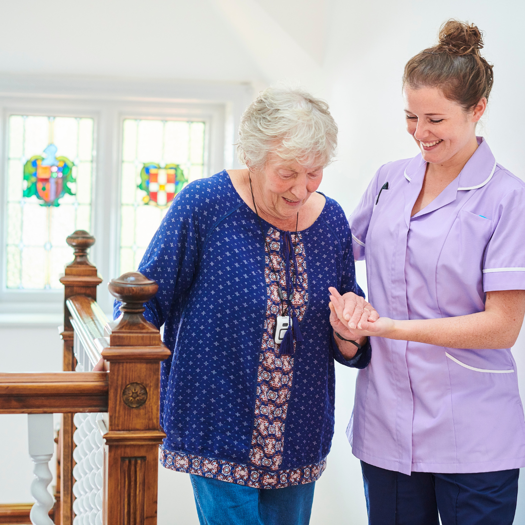 A nurse is helping an elderly woman walk down a staircase.