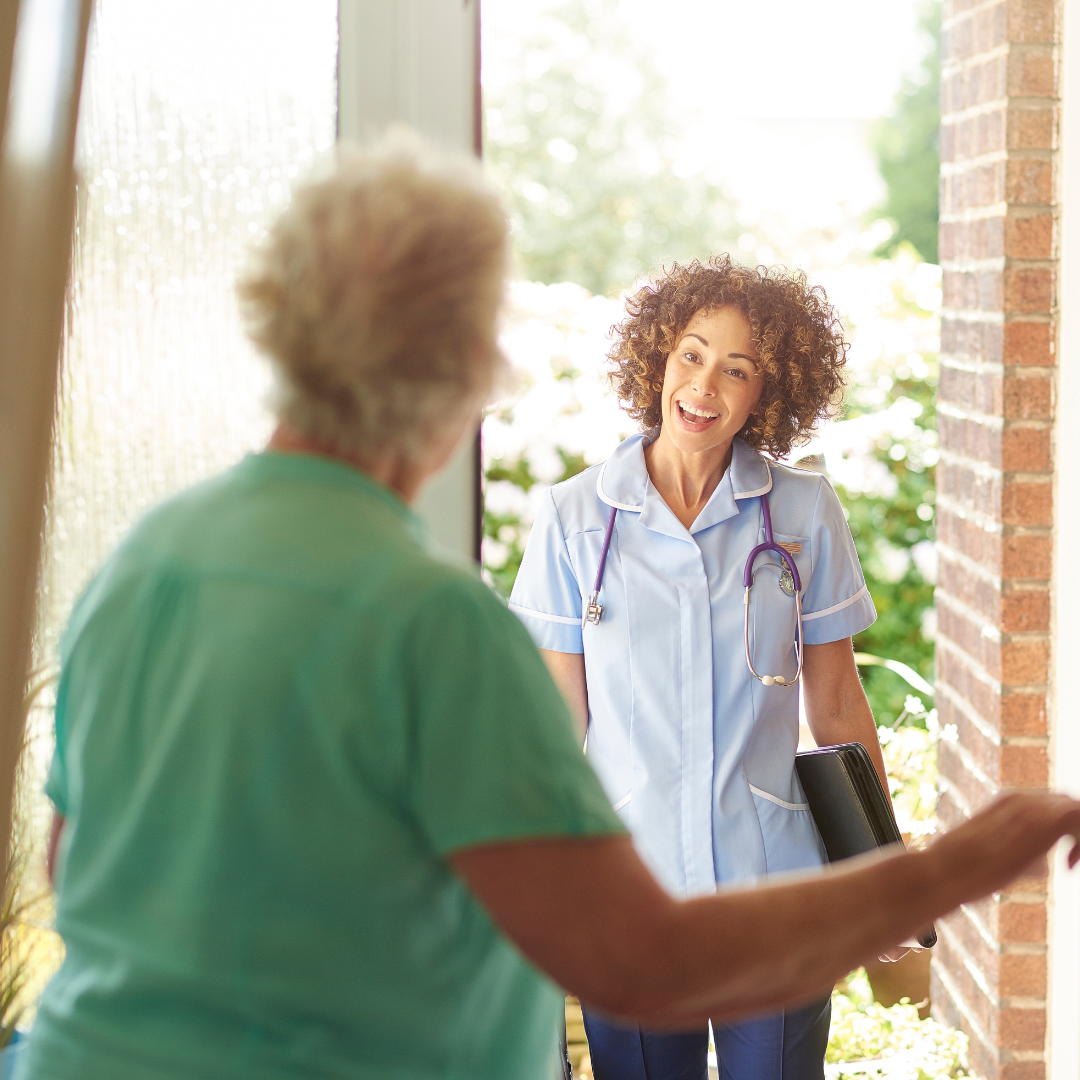 A nurse is talking to an elderly woman in a doorway.