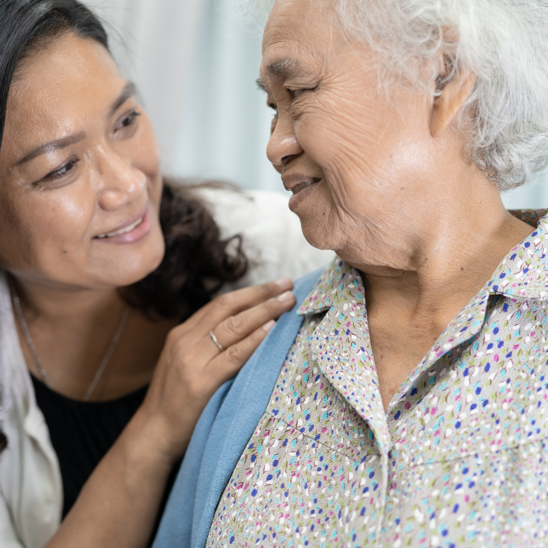 A woman is putting her hand on an older woman 's shoulder.