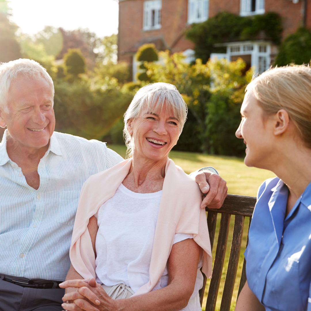 A man and two women are sitting on a bench and smiling